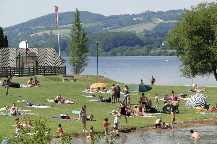Zonnebadende mensen aan een meer met heuvels op achtergrond